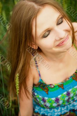 Portrait of young woman stands in a field of wheat with joy