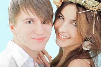 Smiling young man embracing his pretty girlfriend wearing hay ha