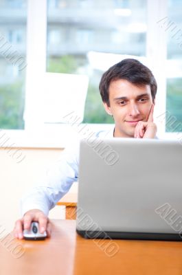A young man sitting in front of a laptop in his office