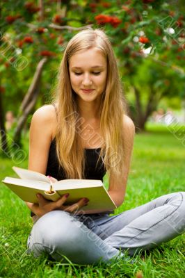 Beautiful female student outdoors with a book at campus park