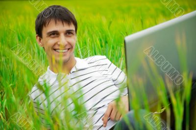 A smiling man with laptop outdoor