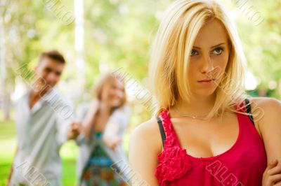 Upset teenage girl being jeered by group of the other young peop