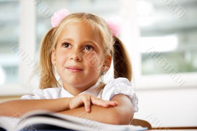 Portrait of a young girl in school at the desk.
