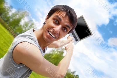 Happy young man with a laptop outdoors