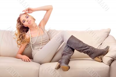 Beautiful woman seated on a sofa in fashionable pose isolated on