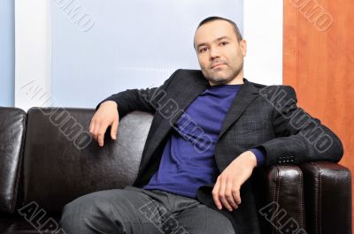 Handsome smiling man seating on the sofa