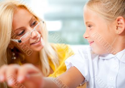 Young pretty teacher helping to her students to make exercise in