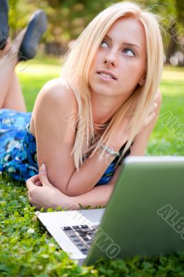 Portrait of young pretty woman resting on green grass at summe