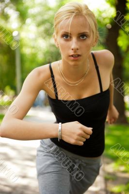 Portrait of young beautiful woman in sportswear running in park.