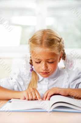 Portrait of a young girl in school at the desk.