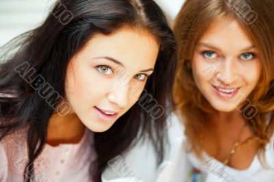 Two women whispering and smiling while shopping inside mall