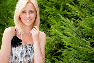 Portrait of a sexy young female smiling in a park against fir tr