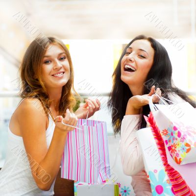 Two excited shopping woman together inside shopping mall. Horizo