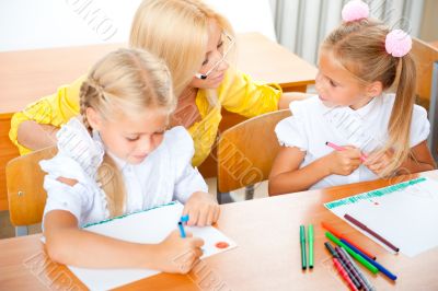 Young pretty teacher helping to her students to make exercise in