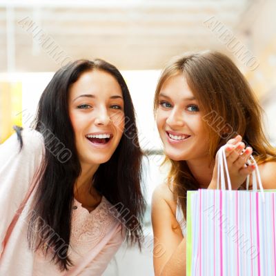 Two excited shopping woman together inside shopping mall. Horizo