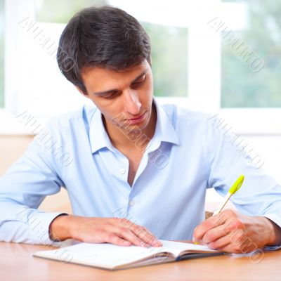 Businessman sitting indoors and writing plan in his diary