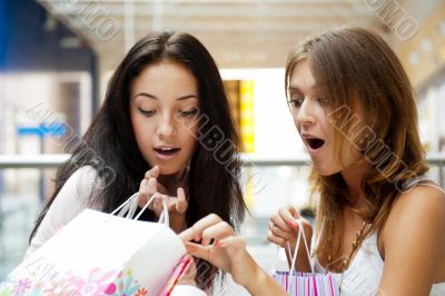 Two excited shopping woman together inside shopping mall. Horizo