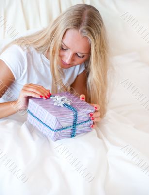 Bedroom surprise present - young happy woman in bedroom