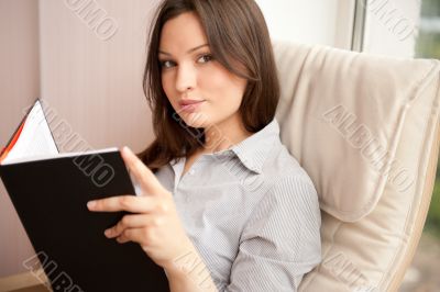 Portrait of a happy young brunette woman holding book