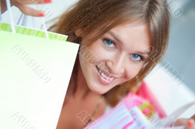 Shopping woman with lots of bags smiles inside mall. She is happ