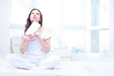 American or european young pretty woman sitting on bed in bright