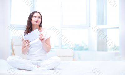 American or european young pretty woman sitting on bed in bright