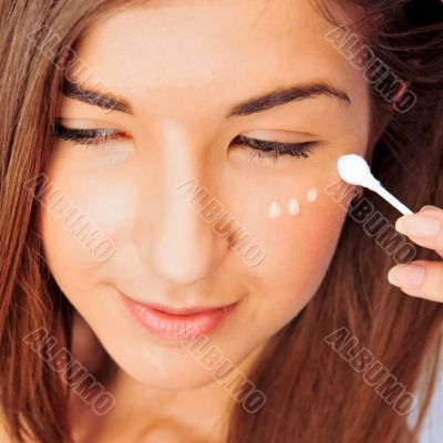Face of beautiful woman with cream on face on white background