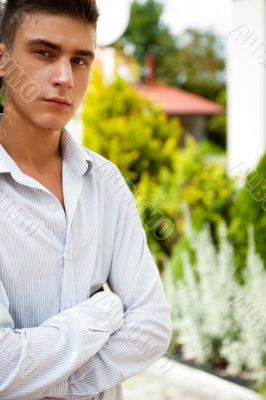 Satisfied smiling businessman standing in the green outdoors.