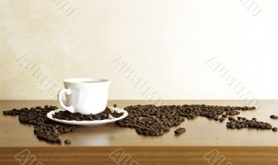 Dramatic photo of world map made of coffee beans. White cup with