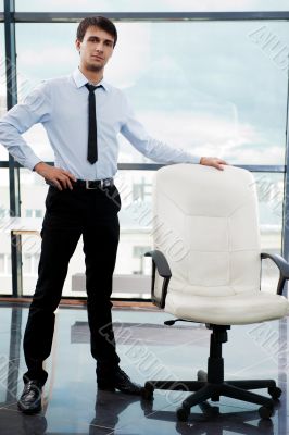 Portrait of confident businessman at his office standing near em