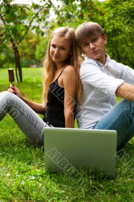 College students using laptop on campus lawn