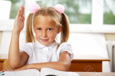 Portrait of a young girl in school at the desk.