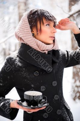 Portrait of young beautiful woman standing alone in winter park 