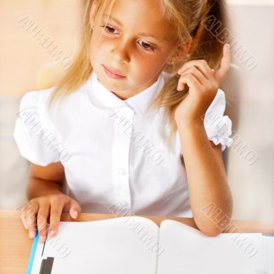 Image of smart child reading interesting book in classroom