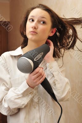 Beautiful woman drying her hair with hairdryer