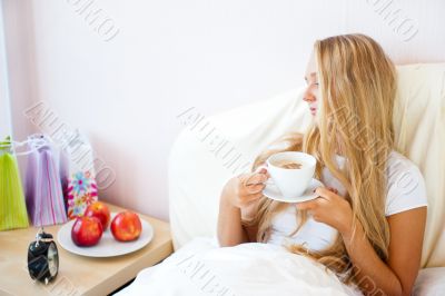 Young woman at home sipping tea or coffee from a cup