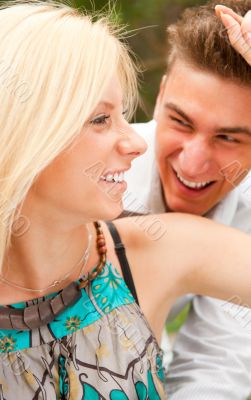 Romantic young couple sitting together in forest and smiling