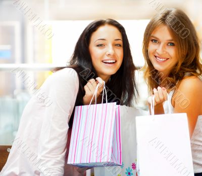 Two excited shopping woman together inside shopping mall. Horizo