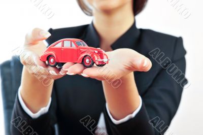 Portrait of young handsome woman holding car in her arms