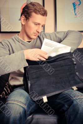 Happy young man sitting on sofa at home 