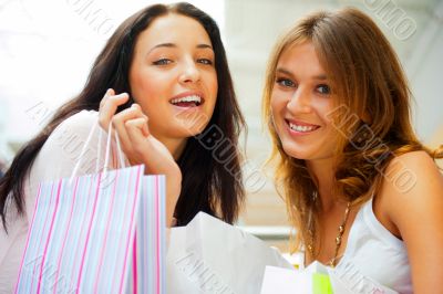 Two excited shopping woman together inside shopping mall. Horizo