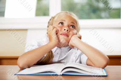 Portrait of a young girl in school at the desk.
