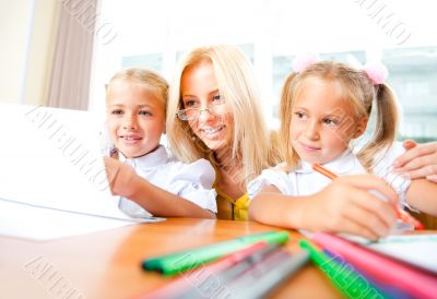 Young pretty teacher helping to her students to make exercise in