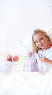 Young happy attractive girl unpack shopping bags in bedroom or h