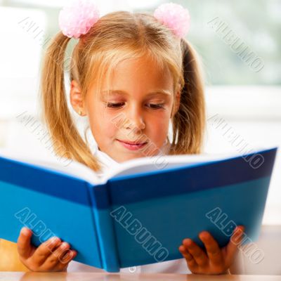 Image of smart child reading interesting book in classroom