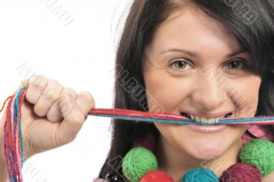 Portrait of a beautiful young girl with colored yarn in her mout