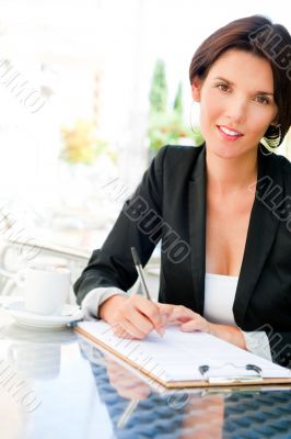 Closeup portrait of pretty woman sitting at cafe and signing doc