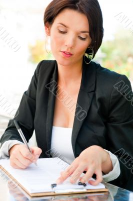 Closeup portrait of pretty woman sitting at cafe and signing doc