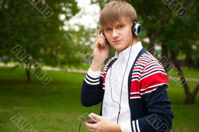 Student listening language course in headphones outside school