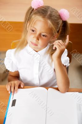 Image of smart child reading interesting book in classroom